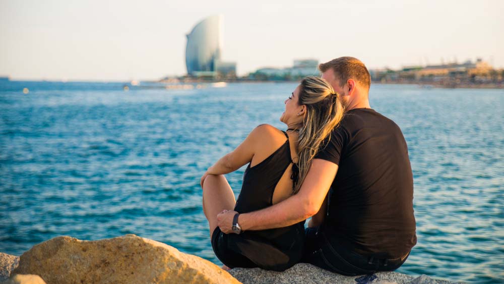 Romantic Things To do in Barcelona a woman sitting next to a body of water
