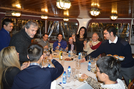 cena-barco-barcelona a group of people sitting at a table with wine glasses