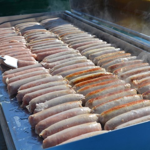 a bunch of hot dogs cooking on a grill on board catamaran