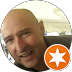 Close-up of a smiling bald man with a beard, overlapping star icon in bottom right corner.